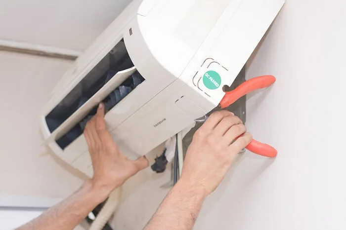 Person's hands fixing an AC unit showing how to recharge AC unit